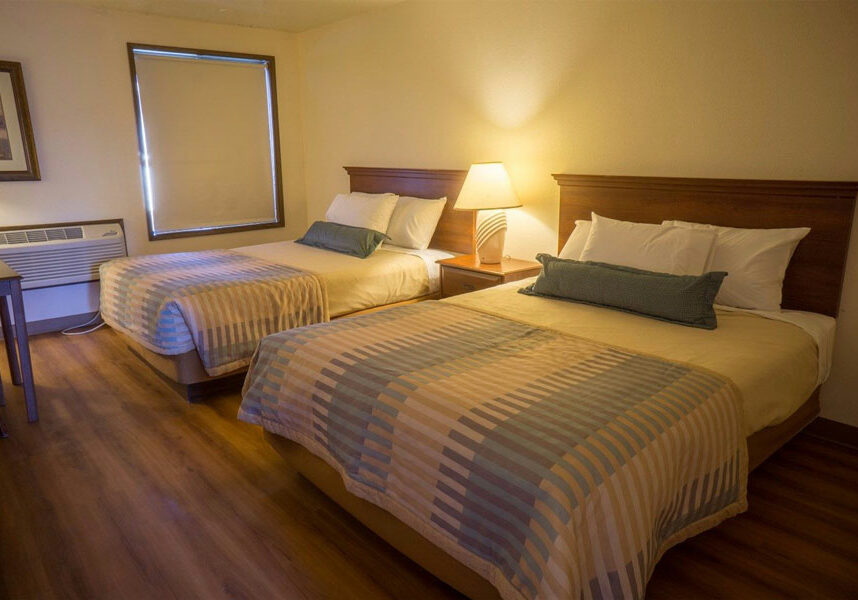 euro two queen room with two queen beds, nightstand in the middle, and window with the shade closed at Sunnyside Inn and Suites